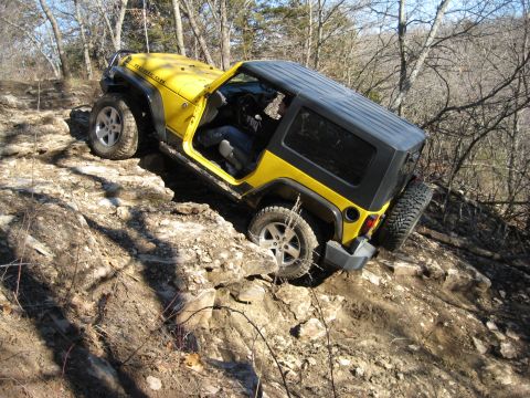 2005 Jeep Wrangler - A yellow Jeep Wrangler Rubicon navigates a challenging rocky terrain on an off-road trail.
