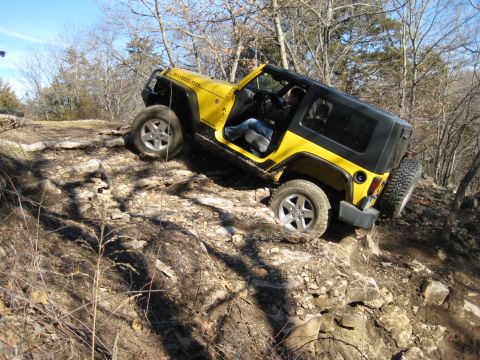 2005 Jeep Wrangler - A yellow Jeep Wrangler navigates a rocky off-road trail with its doors removed.