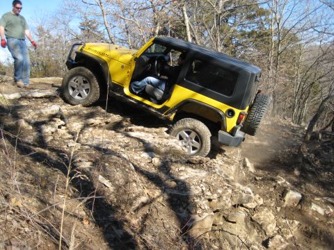 2005 Jeep Wrangler - A yellow Jeep Wrangler Rubicon tackles a challenging rocky terrain on an off-road trail.