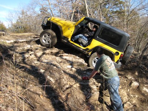 2005 Jeep Wrangler - A yellow Jeep Wrangler navigates a challenging rocky terrain with assistance from a spotter.