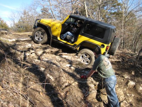 2005 Jeep Wrangler - A yellow Jeep Wrangler Rubicon navigates a challenging rocky off-road course with a person observing.