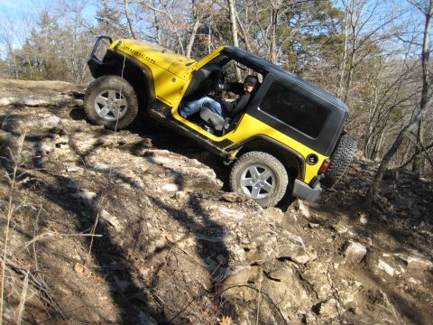 2005 Jeep Wrangler - A yellow Jeep Wrangler Rubicon navigates a rocky off-road trail.