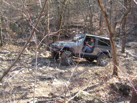 2005 Jeep Wrangler - Jeep Wrangler navigating a rough, rocky path through a wooded area.