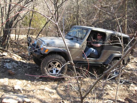 2005 Jeep Wrangler - A Jeep Wrangler Rubicon navigates a rough, wooded terrain on an off-road trail.