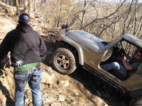 2005 Jeep Wrangler - A Jeep Wrangler Rubicon navigates a steep, rocky off-road trail with a person watching.