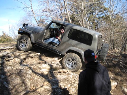 2005 Jeep Wrangler - A gray 2005 Jeep Wrangler navigates a rocky off-road trail with a driver behind the wheel.