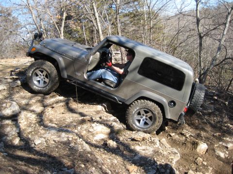 2005 Jeep Wrangler - A gray 2005 Jeep Wrangler navigates a challenging rocky trail with its driver at the wheel.
