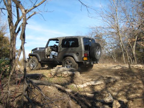 2005 Jeep Wrangler - 2005 Jeep Wrangler navigating a challenging off-road course through a wooded area.