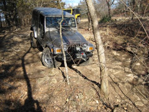 2005 Jeep Wrangler - Two Jeeps navigate a wooded, rocky off-road trail on a sunny day.
