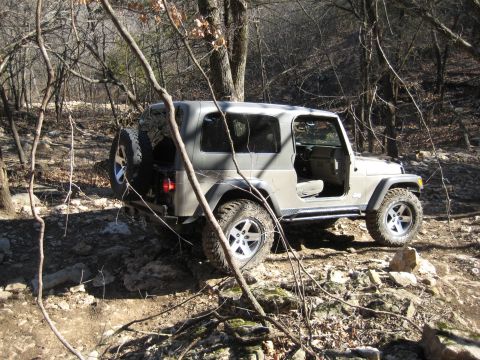2005 Jeep Wrangler - A Jeep Wrangler navigates a rocky, wooded trail, its off-road capabilities.