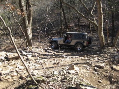 2005 Jeep Wrangler - A Jeep Wrangler navigates a challenging, rocky path through a dense forest environment.