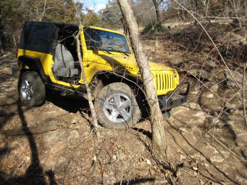 2005 Jeep Wrangler - A yellow 2005 Jeep Wrangler Rubicon navigates a challenging rocky terrain on a sunny day.