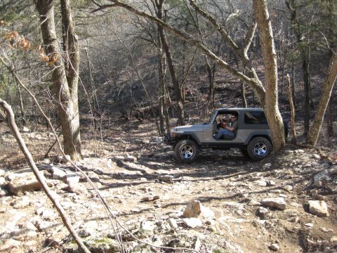 2005 Jeep Wrangler - A gray 2005 Jeep Wrangler is parked on a rocky, wooded trail, appearing to be off-roading.