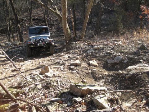 2005 Jeep Wrangler - A Jeep Wrangler navigates a challenging, rocky trail through a forest.