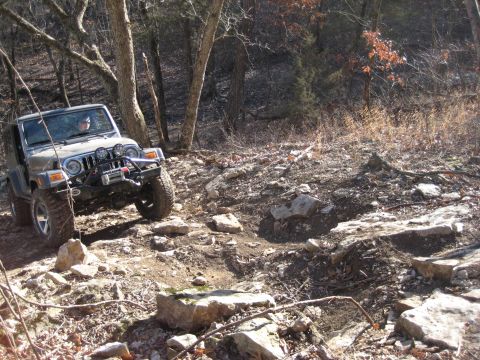 2005 Jeep Wrangler - Jeep Wrangler tackling a challenging rocky trail in a wooded area.