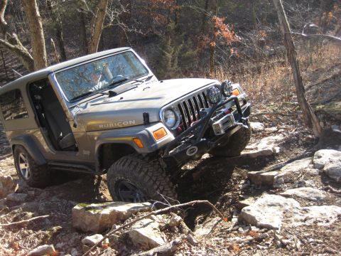 2005 Jeep Wrangler - A Jeep Wrangler Rubicon navigates a challenging rocky trail in a wooded area.