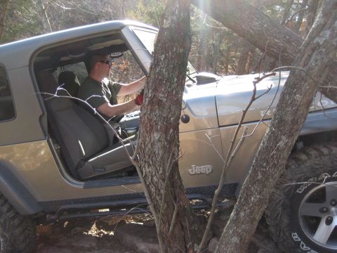 2005 Jeep Wrangler - Driver maneuvers a 2005 Jeep Wrangler through a wooded, rocky off-road path.
