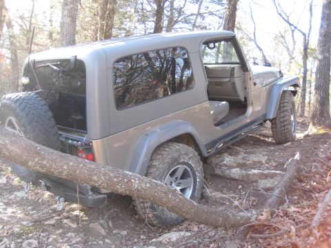 2005 Jeep Wrangler - A Jeep Wrangler navigates a challenging off-road course, with a fallen tree obstructing its path.