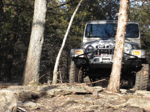 2005 Jeep Wrangler - A Jeep Wrangler navigates a rocky, wooded path, its off-road capabilities.