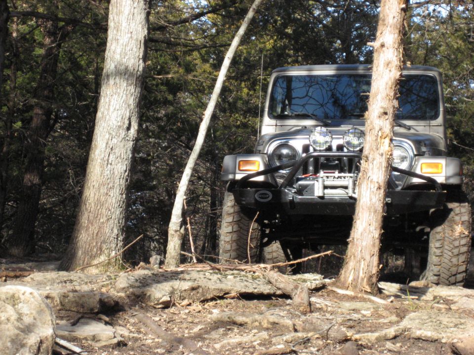 Jeep Wrangler on rocky trail, trees around