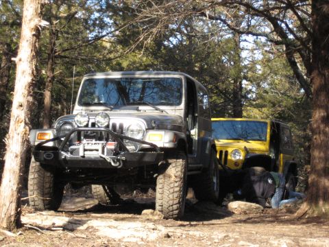 2005 Jeep Wrangler - Two Jeep Wranglers are parked on a dirt trail surrounded by trees.