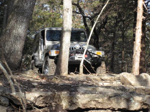 2005 Jeep Wrangler - A Jeep Wrangler navigates a challenging rocky path through a wooded area.