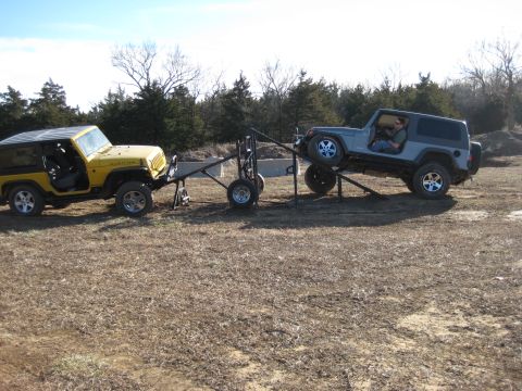 2005 Jeep Wrangler - Two Jeep Wranglers are connected by a trailer, with one vehicle loaded onto the trailer.