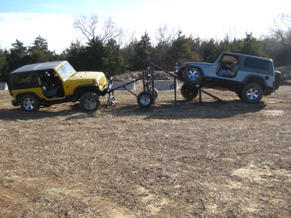 Yellow Jeep Wrangler being towed by a gray Jeep Wrangler on a trailer rig