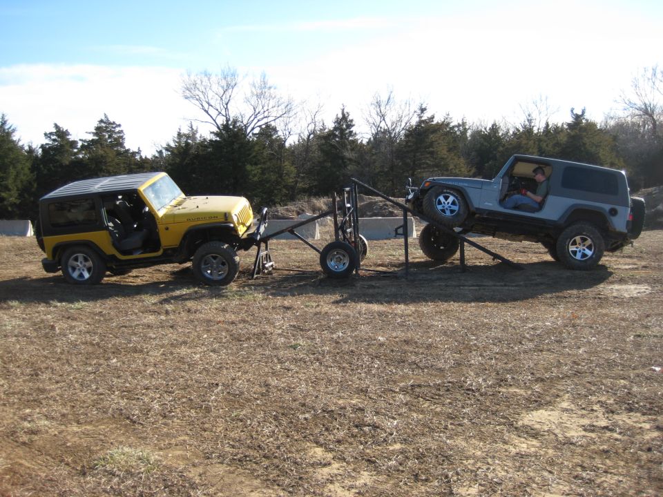 Yellow Jeep Wrangler and gray Jeep Wrangler on an obstacle course with a trailer