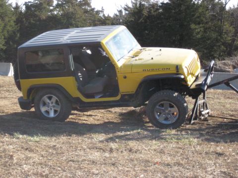 2005 Jeep Wrangler - This yellow Jeep Wrangler, likely a 2007 or newer model, is parked outdoors with its driver's door ajar.