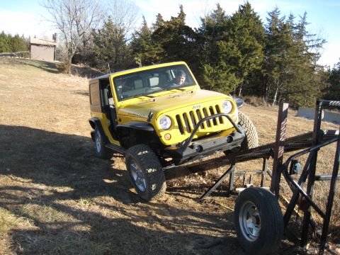 2005 Jeep Wrangler - A yellow Jeep Wrangler is positioned on an inclined metal structure, with its front-left side angled towards the camera.