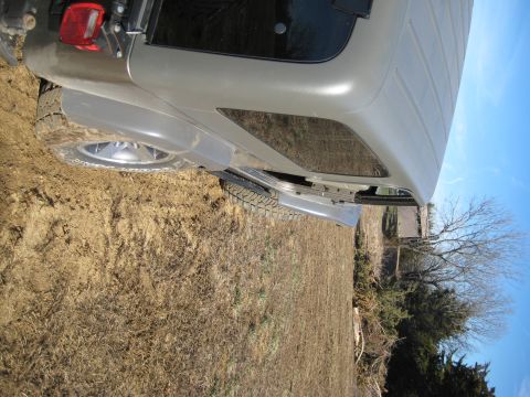 2005 Jeep Wrangler - Rear view of a 2005 Jeep Wrangler parked on muddy terrain under a clear blue sky.