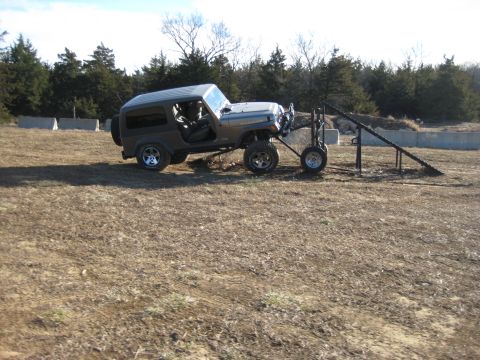 2005 Jeep Wrangler - A gray Jeep Wrangler is positioned on an off-road course, with a trailer attached to its rear bumper.