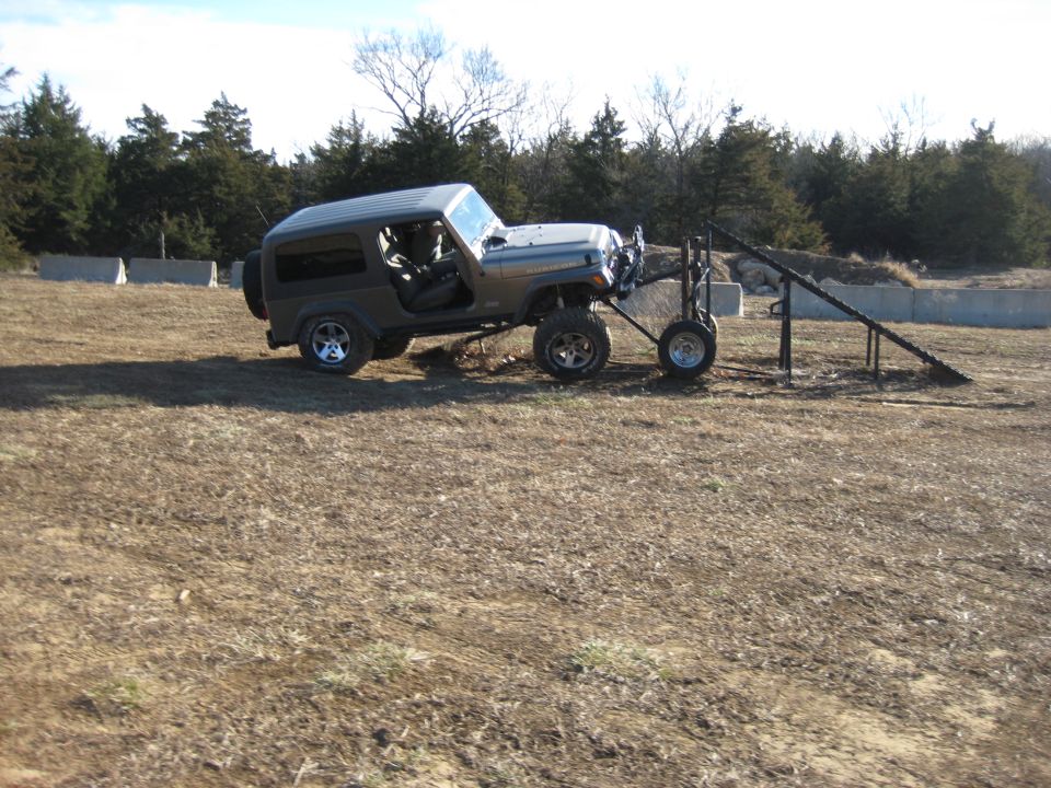 Gray Jeep Wrangler with trailer on uneven terrain