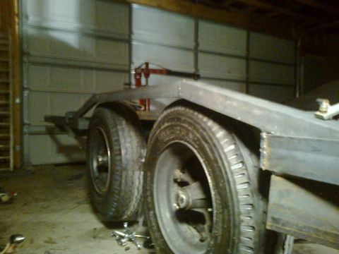 1990 Ford Bronco - A trailer chassis with dual wheels is visible in a garage setting.