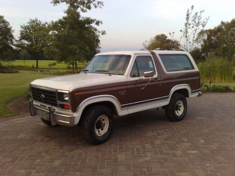 1984 Ford Bronco - This two-tone brown and white Ford Bronco is seen from a three-quarter front view, parked on a brick patio.