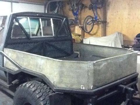 1988 Suzuki Samurai - The rear of a truck with a custom metal bed and roll bar is shown in a garage.