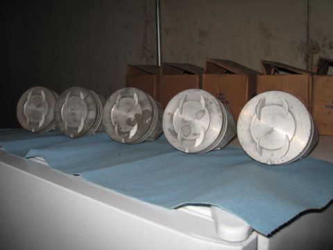 1963 Ford Galaxie - Set of five pistons displayed on a blue cloth with cardboard boxes in the background.