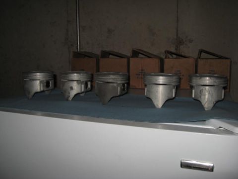 1963 Ford Galaxie - Five pistons are displayed on a blue cloth, with cardboard boxes stacked behind them.