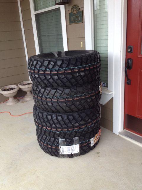 1991 Ford Bronco - Four new off-road tires are stacked on a porch, awaiting installation.