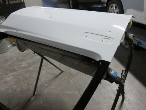 1987 Dodge 1500 - A freshly painted white vehicle door rests on a stand, awaiting reinstallation.