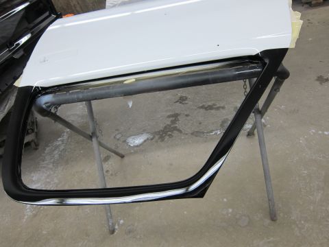 1987 Dodge 1500 - A white truck door with black trim is shown on a stand, likely undergoing repair or painting.