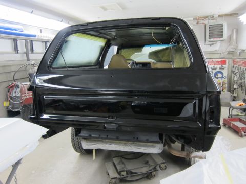 1987 Dodge 1500 - Rear view of a black SUV in a workshop, likely undergoing body repairs or restoration.