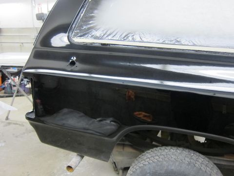 1987 Dodge 1500 - Close-up of a black SUV's rear quarter panel, showing bodywork in progress.