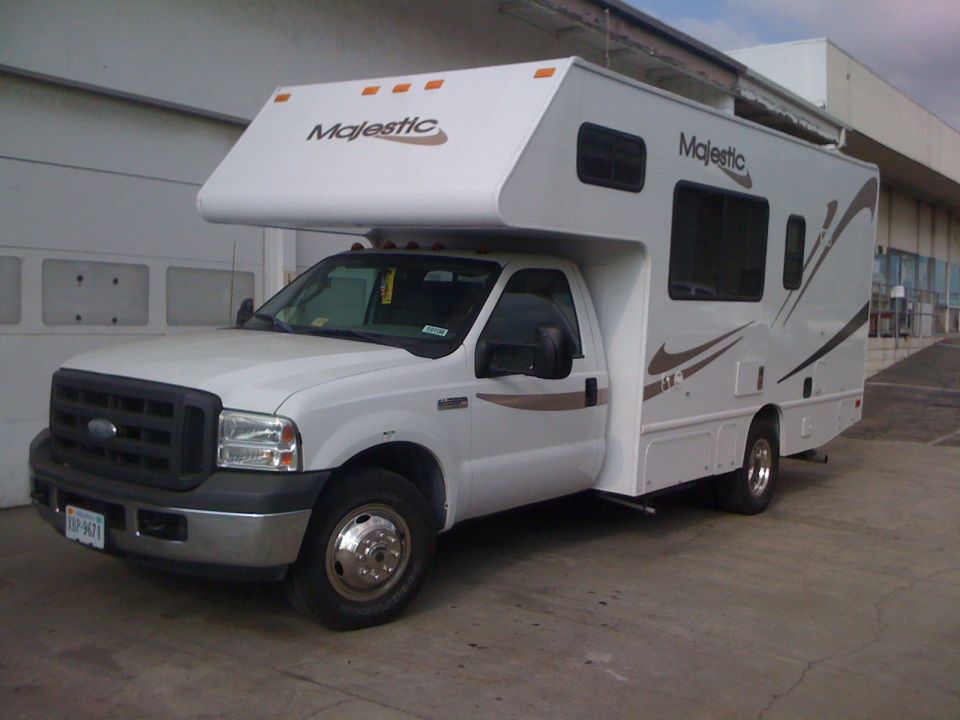 White Ford E-Series cutaway van with a RV camper body. Front view, driver's side