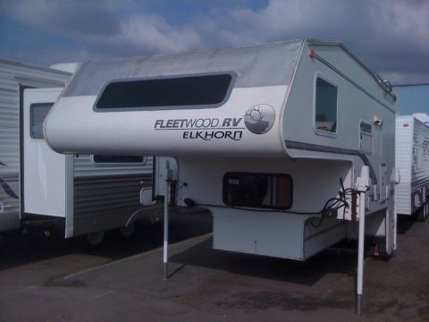 1968 Ford Mustang - A Fleetwood RV Elkhorn truck camper is parked next to another RV under a cloudy sky.