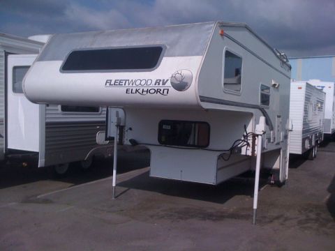 1968 Ford Mustang - A Fleetwood RV Elkhorn truck camper is parked in a lot with other RVs.