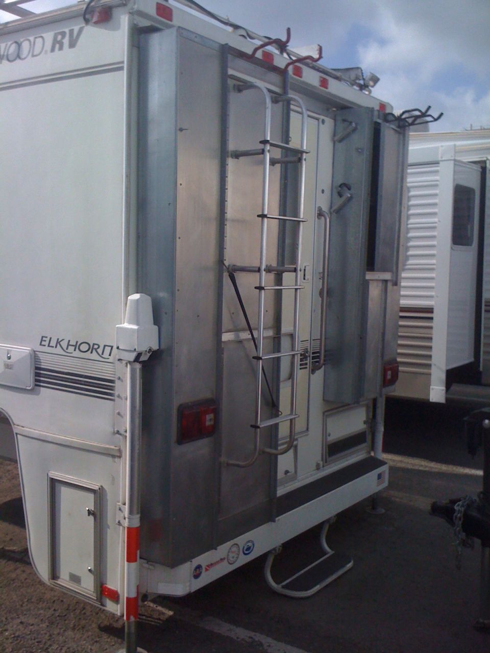 Rear view of an Elkhorn RV truck camper with a ladder and storage compartments