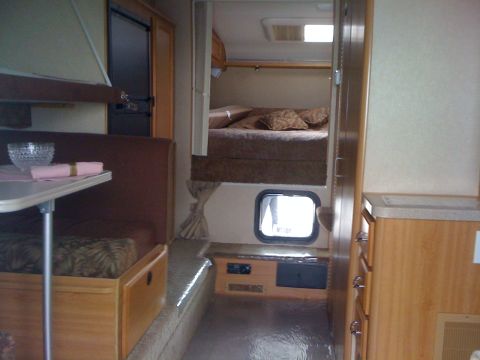 1968 Ford Mustang - Interior view of a truck camper with sleeping quarters and a dinette area.