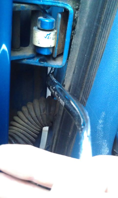 1990 Ford Bronco - Close-up of a blue door hinge mechanism with visible text on a black cable conduit.